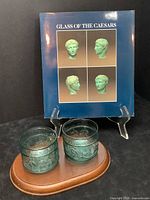 Photo showing book titled 'Glass of the Caesars' standing behind two green glass tumblers on a wooden tray.