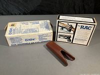 Photo of boxed Shooting Chrony chronograph next to boxed The RAC firearms locking system and Galco leather barrel guard.