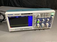 Front view of Hantek DSO5202P oscilloscope powered on with user interface displayed on screen.