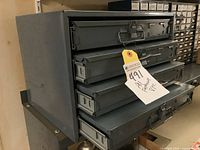 Grey metal 4-drawer cabinet with tag attached