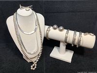 All pieces displayed: three necklaces on bust, bracelets and earrings on stand