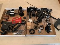 Full view of the lot contents showing Nikon camera body, motor drive, multiple lenses, microscope lenses and various small items arranged in two trays.