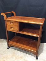 View of the rosewood tea cart showing the front with two drawers, two shelves, and casters