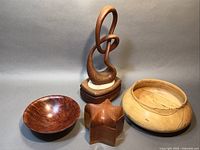 Overview of the four wooden art pieces showing the sculpture, two bowls, and trinket box arranged together.