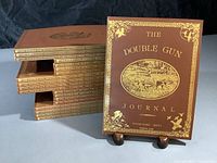 Stacked 20 issues of The Double Gun Journal with one issue displayed upright showing cover design and title.
