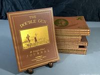 Front view of The Double Gun & Single Shot Journal magazines stacked and standing, showing gold embossed cover with hunting illustration.