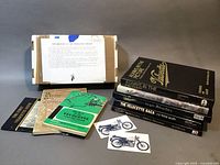 Overview of all items including model kit box with instruction sheet, five Velocette-related books, and two magnets with motorcycle images.