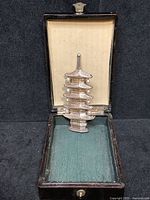 Brooch presented upright inside original lacquer box showing interior lining and brooch details.