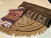 Three vintage textiles displayed on a flat surface showing distinctive patterns and colors.