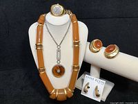 Universal Geneve watch displayed with three necklaces and two pairs of earrings on display stand