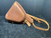 Front view of triangular leather holster with closed flap and brass twist-lock
