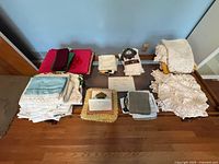 Overall view of various folded linens including doilies, overlays, towels and napkins arranged on the floor