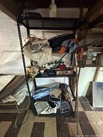 Full frontal image of black metal shelving unit with various items on shelves obstructing view. Shows four shelves with open side design and boltless metal frame.