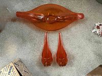 Top-down view of the full three-piece set showing the curved centerpiece bowl and two matching taper candle holders on a carpeted floor