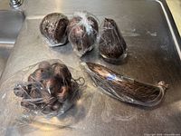 Four carved wooden fruit items wrapped in original plastic: apple, pear, banana, and grapes cluster laid out on a surface.