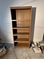 Front view of tall 5-shelf oak finish bookcase, showing all shelves and wood grain detail.