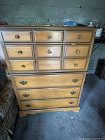 Front view showing the nine-drawer maple dresser with three rows of round brass knob handles on top six drawers and three lower drawers with bail pull handles.