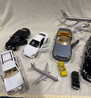 View of 9 diecast vehicles including passenger cars, SUV, compact car, and model aircraft.