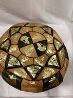 Close-up of one round ottoman/floor cushion showing tan and black fabric panels with gold metallic embossed Egyptian motifs and symbols.