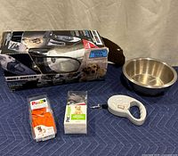 Black+Decker Dust Buster Retriever vacuum in box with pet accessories including orange rubber dog boots, adjustable harness in box, retractable leash, and stainless steel dog bowl