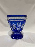 Front view of a cobalt blue cut-to-clear vase with starburst patterns on its flared open bowl shape and solid base.