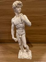 Front view of white resin statue replica of Michelangelo's David showing detailed musculature and facial features standing on a rectangular base.