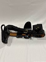 Full view of black leather holster belt with attached gun holster and magazine pouch with brass hardware.