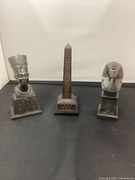 Front view of the three Egyptian-themed metal figurines showing detailed designs and bases.