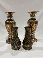Set of four Egyptian decorative vases showing overall size and design, two large and two smaller vases with mixed metal inlay and contrasting motifs.