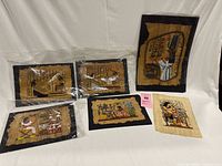 Photo showing six Egyptian papyrus paintings laid on white cloth, including some with black matting, depicting various ancient Egyptian figures and hieroglyphics.
