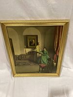 Framed oil painting showing two women inside a classical-style room, wood frame gold-tone finish