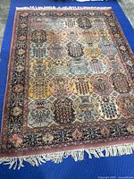 Full view of rug on blue protective mat showing overall pattern and fringe