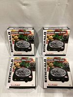 Four boxed Emerald electric single stoves displayed stacked in two rows, boxes indicating model and product features.