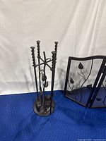Metal fireplace tool holder stand with twisted handles and leaf decorative accents in dark bronze.