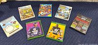 All items in the lot displayed on a dark cloth including video games and DVD in cases, colorful covers visible