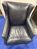 Front view of dark leather armchair showing seat cushion and wingback design