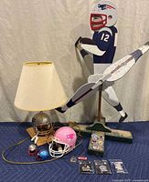 Patriots yard whirlybird wooden decor, lamp with football helmet base, four mini helmets, and collectible pins arranged on blue surface