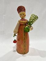 Full-front view of the entire Russian Matryoshka doll showing dress, headdress, and vase.