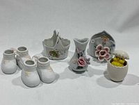 Full lot showing 2 pairs of baby shoe figurines, 2 floral baskets, 1 floral vase, and chick shaker