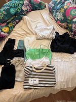 12 pieces of women's clothing laid out on bed including leggings, tops, skirt, and shorts