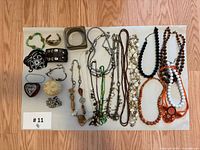 Top-down view of entire lot laid on flat surface showing multiple necklaces, bangles, cuff bracelets, pendants, and small accessories.