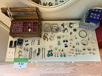 Full display of the jewelry lot laid out on a table showing earrings, bracelets, rings, brooches, and two jewelry boxes.
