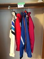 Side and back view of 7 women's jackets hanging on a closet rod showing different colors and designs.