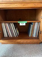 Wooden cabinet with two shelves holding vintage LP records primarily rock and musical genres.