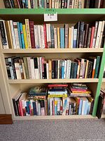Three shelves filled with various paperback and some hardcover fiction books, showing a wide range of book titles and authors.
