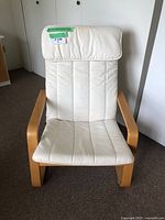 Frontal view of the IKEA Poang chair showing padded light beige seat and backrest with natural wood armrests and frame.