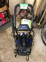 Front angled view of the Kobalt pressure washer showing handle, wand, hose, and attached documentation.