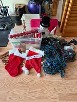 Photo of assorted Christmas decor including stockings, outdoor lights, snowman decoration, red ornaments, and craft supplies.
