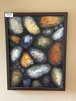 Full view of the framed painting showing nature-inspired abstract stones in multiple colors.