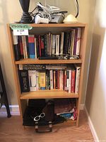 Front view of pine wood 3-shelf bookshelf with books and items on shelves.